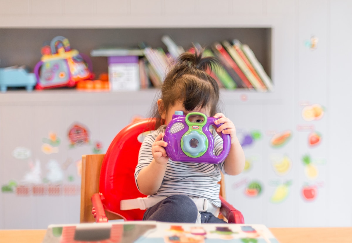 Young girl exploring with a colorful toy camera